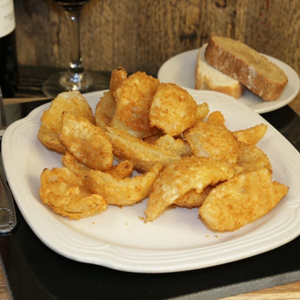 A plate of golden-brown fried calamari, a fork, bread, and a glass of red wine.